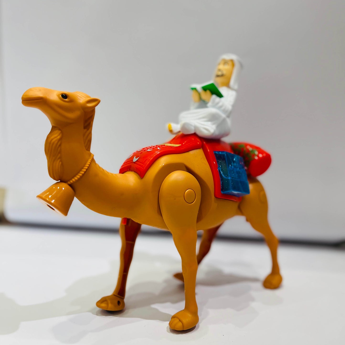 Toy figure of a person riding a camel on a plain background