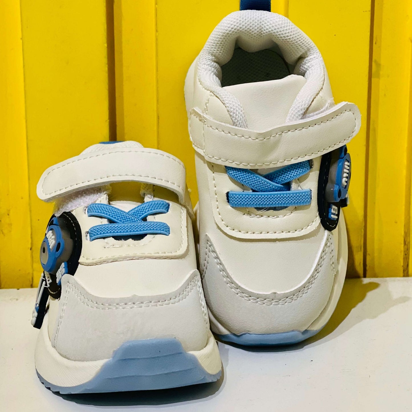 White sneakers with blue laces and soles on a yellow background
