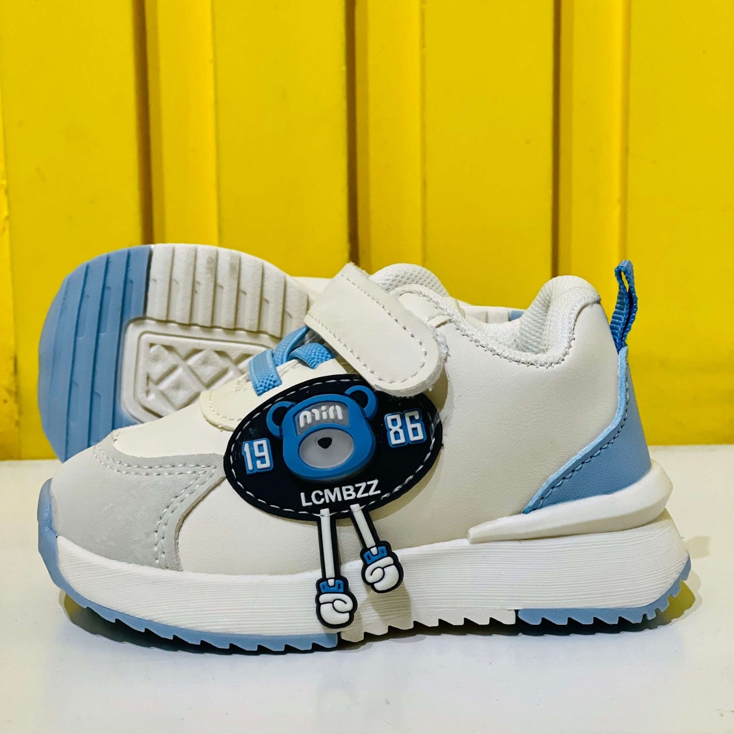 Children's white and blue sneakers with a cartoon character on a yellow background