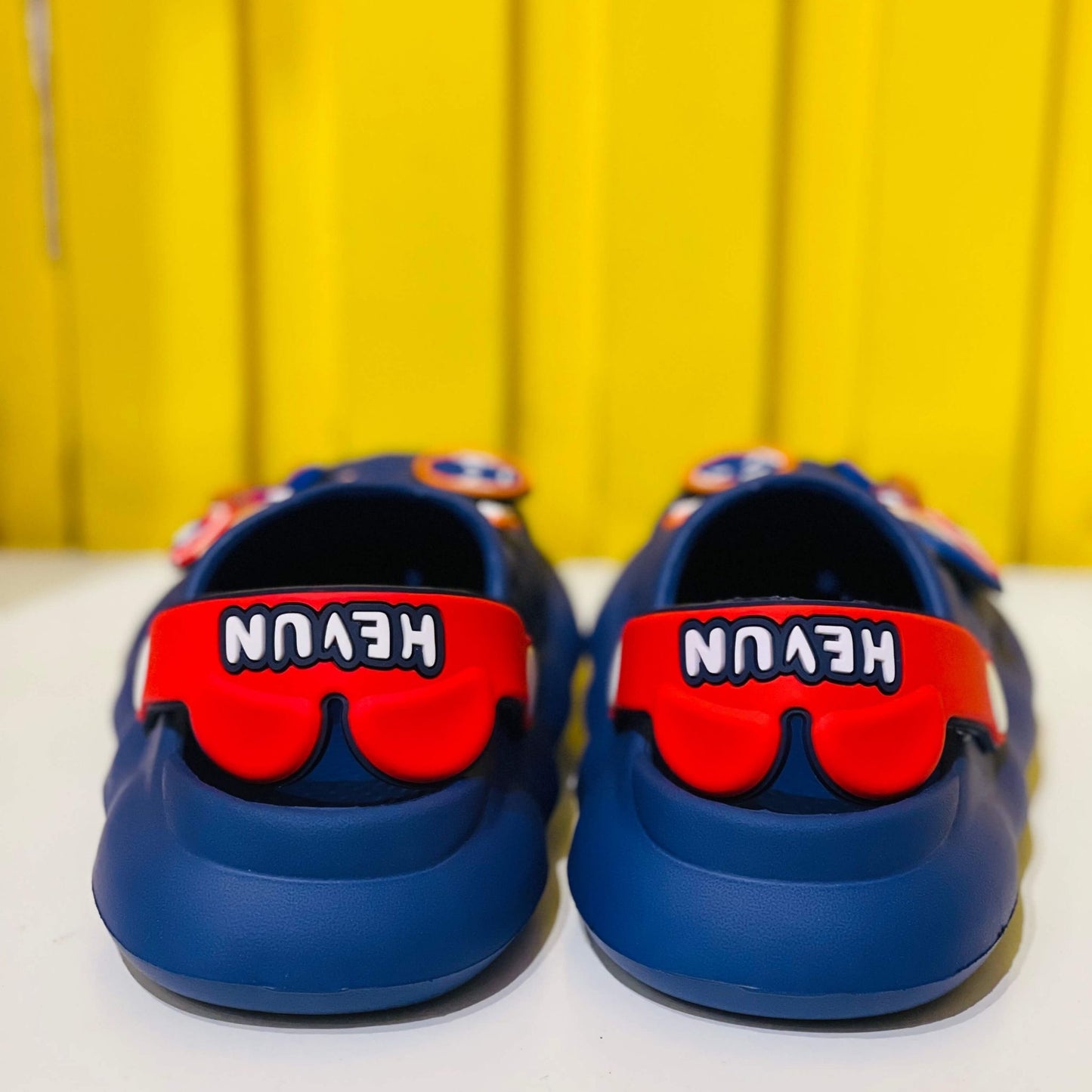Blue shoes with red visors and 'HEVUN' branding on a yellow background