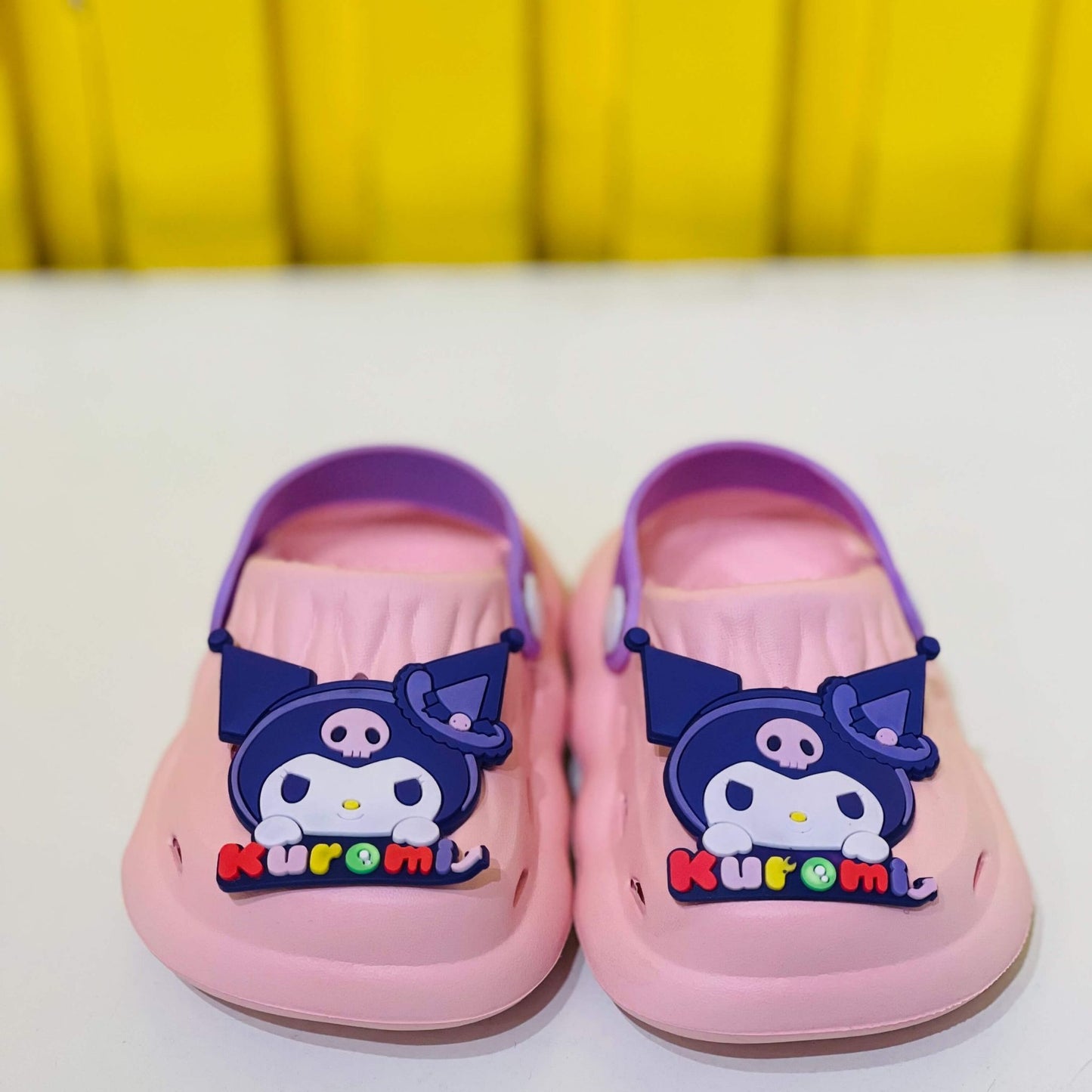 Pink children's shoes with cartoon character and 'Kuromi' branding on a white background.