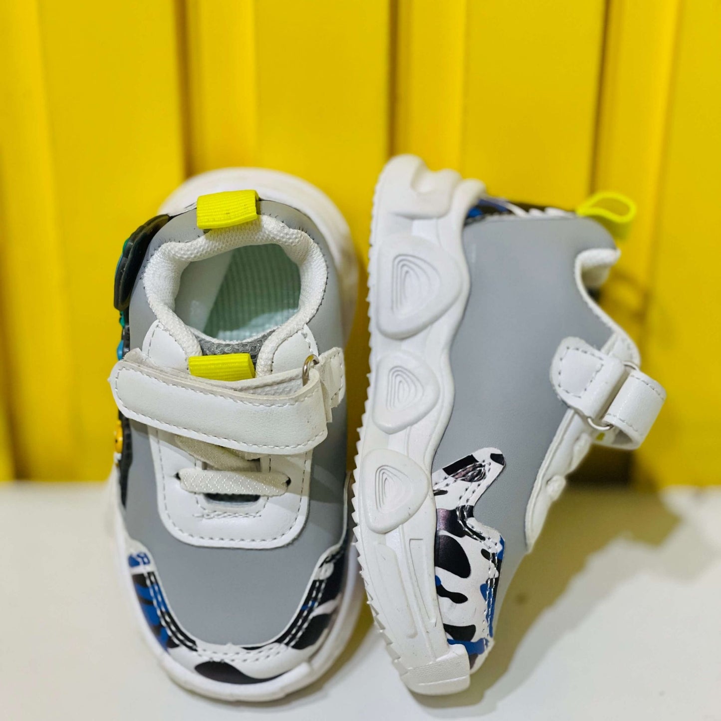 Children's sneakers with white and gray design on a yellow background