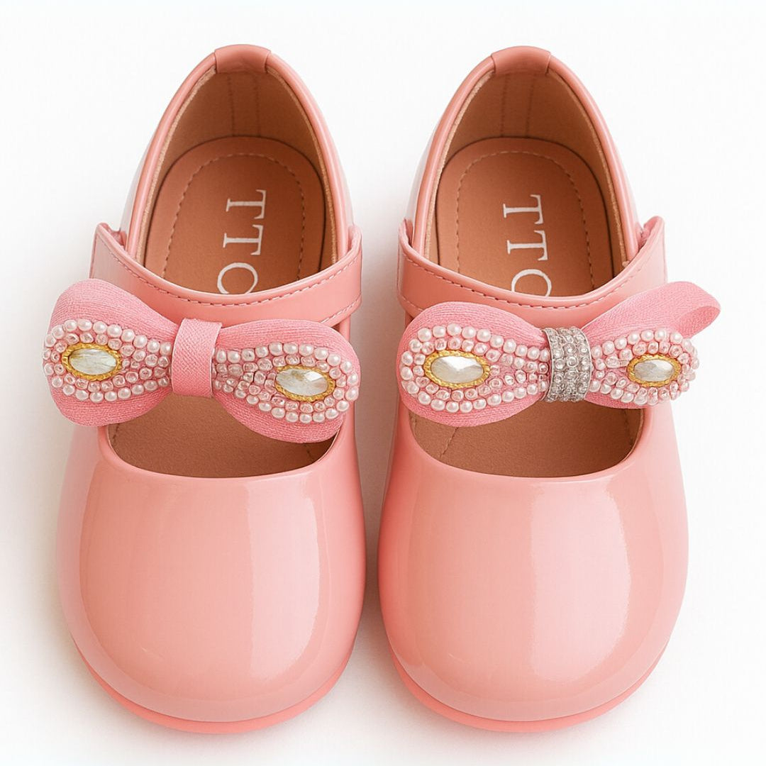 Pink children's shoes with decorative bows on a white background