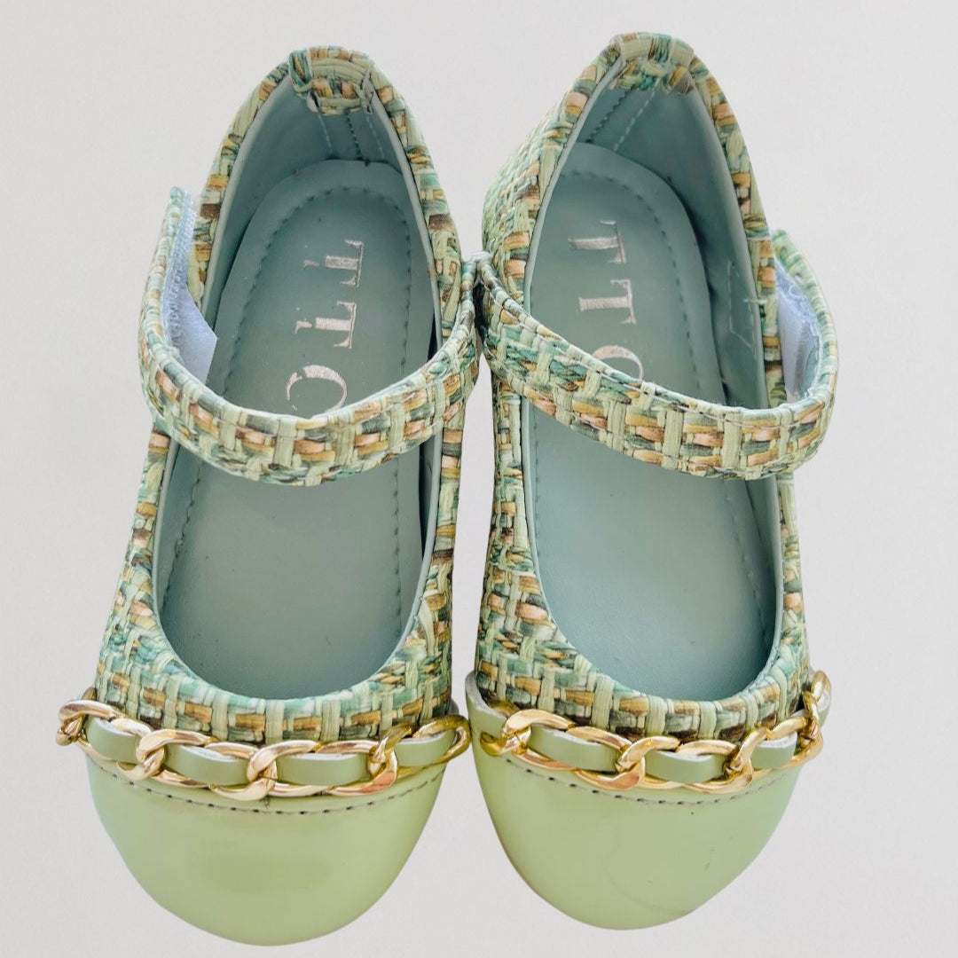 Pair of green shoes with woven design and gold chain details on a light gray background