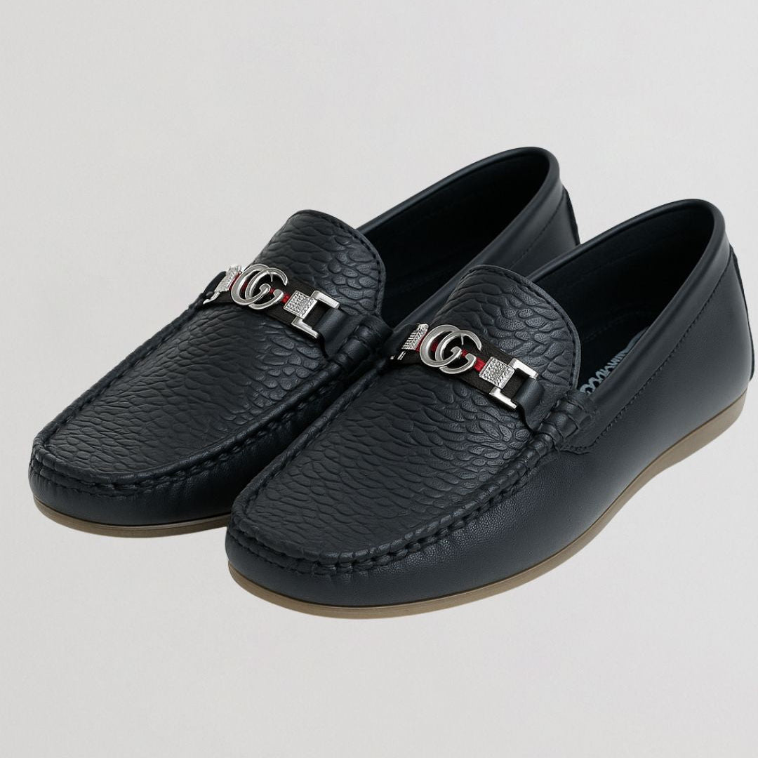 Black leather loafers with brand logo on a light gray background