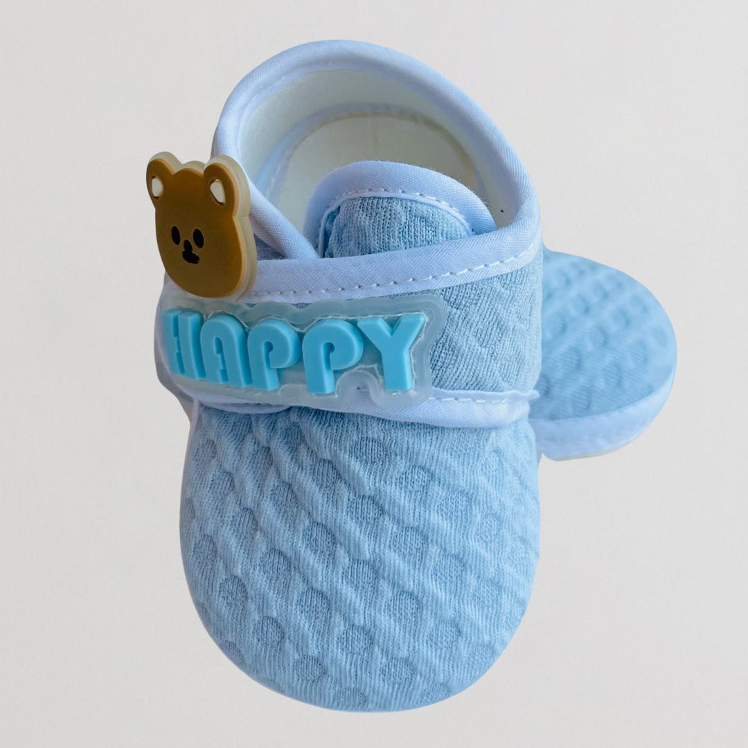 Blue baby shoe with a bear tag and 'Happy' text on a light gray background