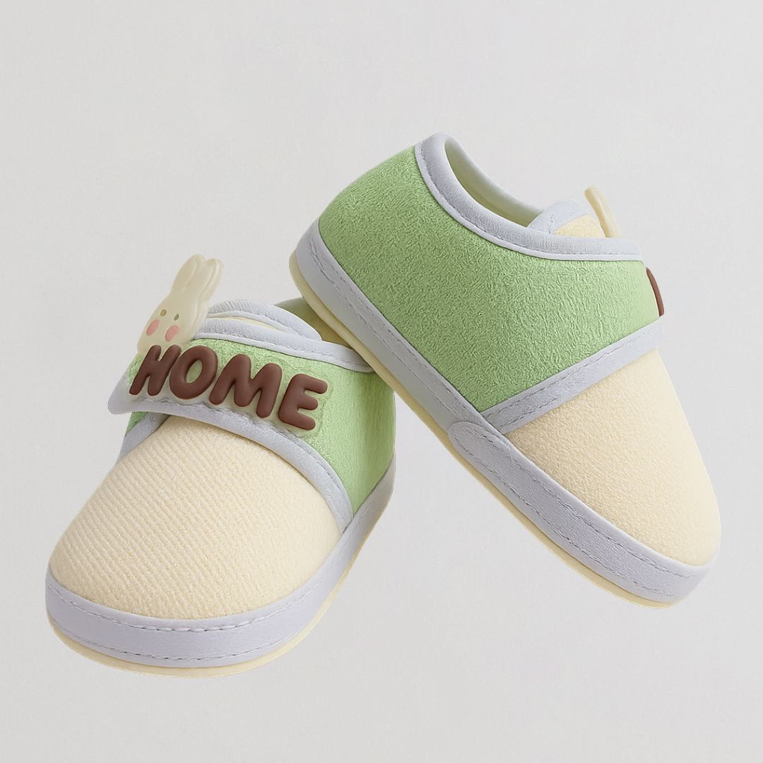 Pair of baby shoes with 'HOME' text on a light gray background