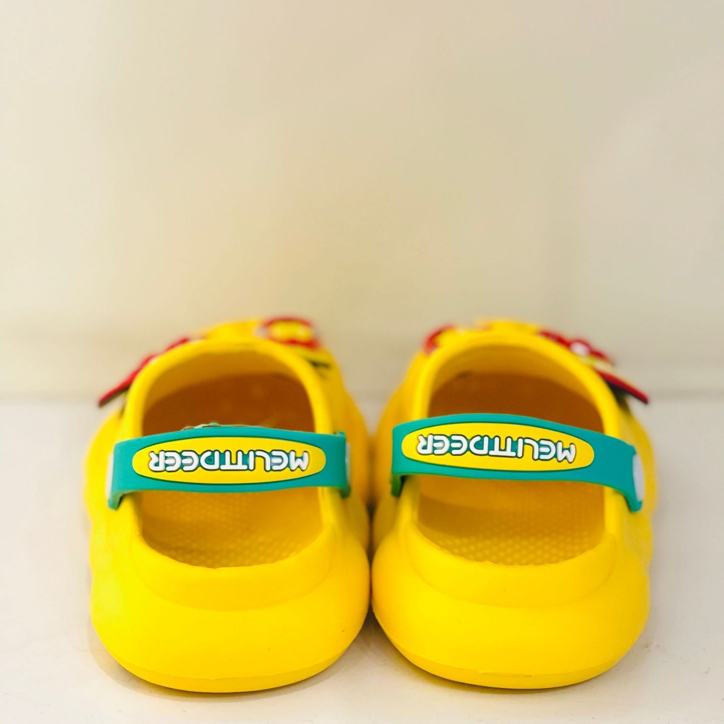 Pair of yellow shoes with teal straps on a white background