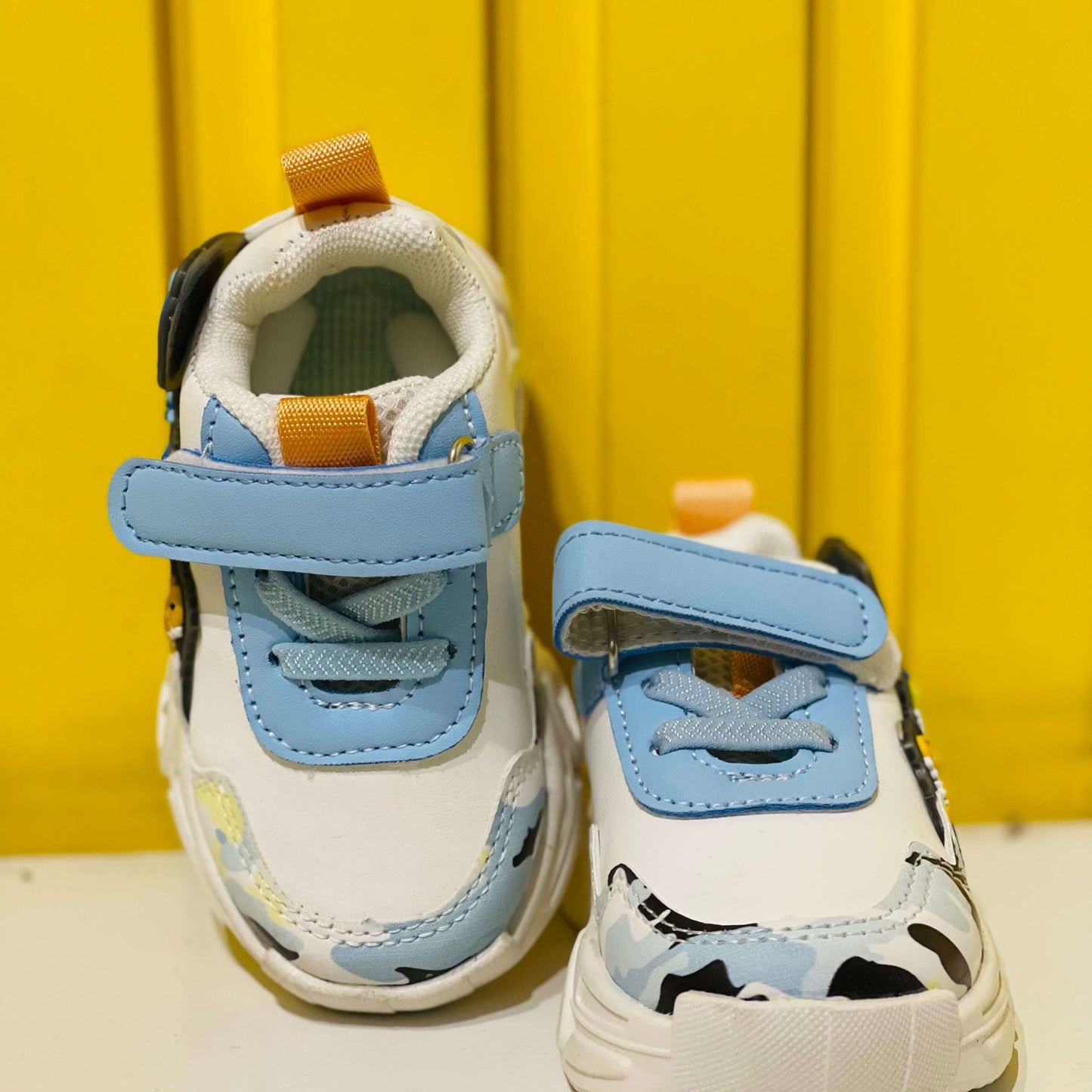 Children's sneakers with blue straps on a yellow background