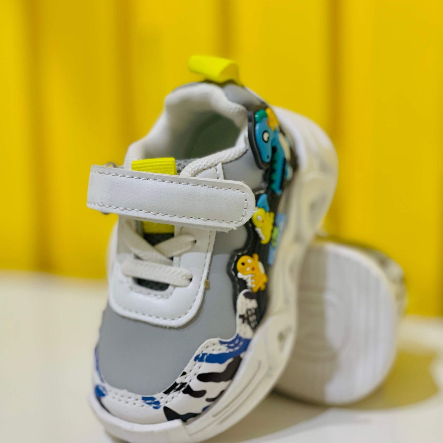 Gray children's shoe with colorful designs on a yellow background
