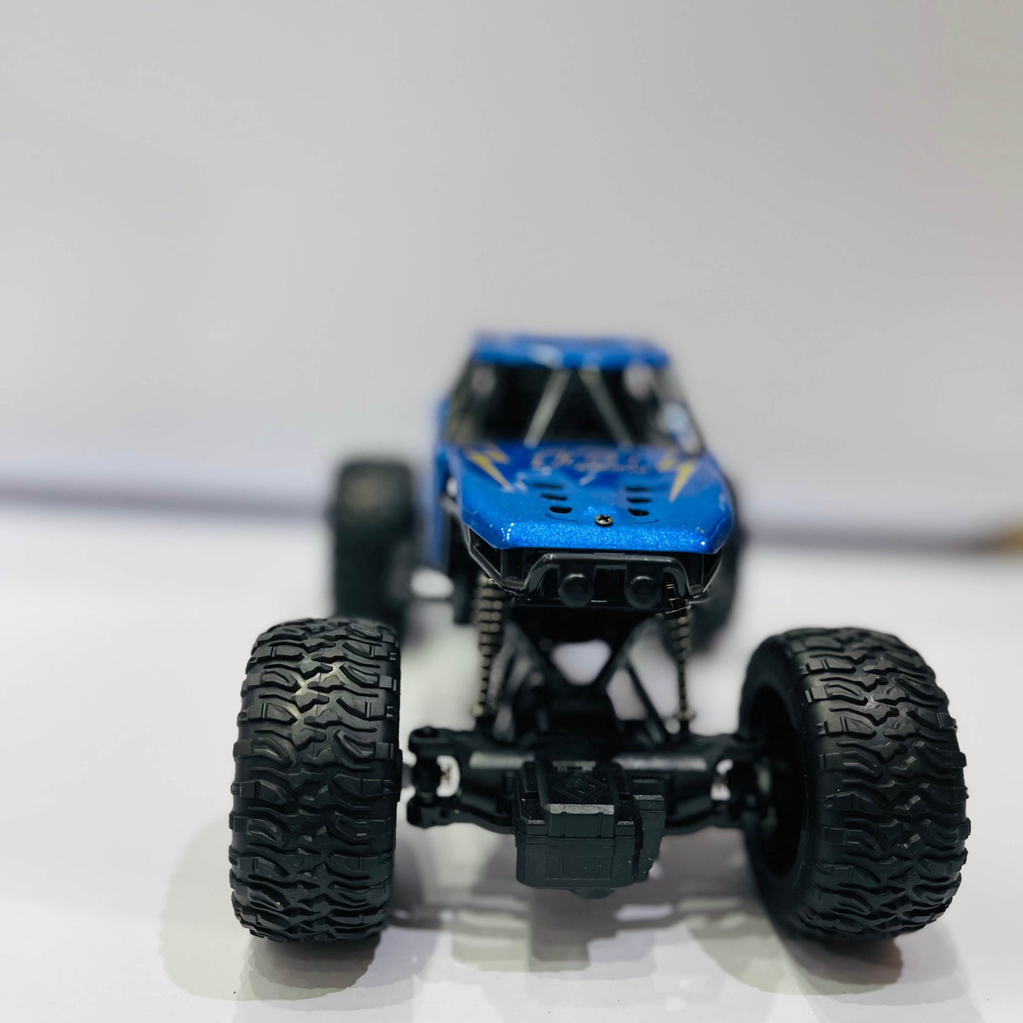 Model of a blue off-road vehicle with large black tires on a white background