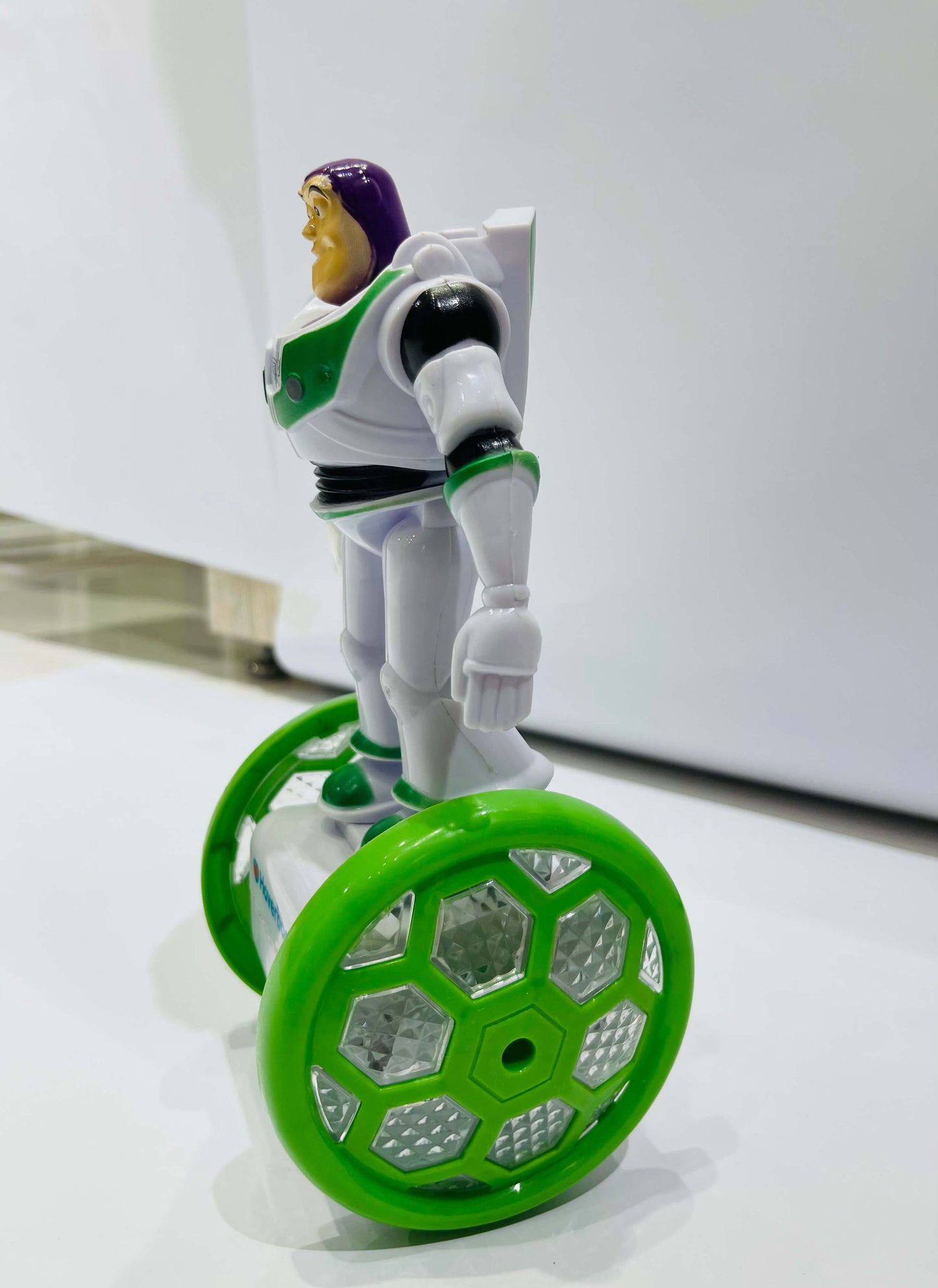 Toy figure on a hoverboard with green wheels against a white background