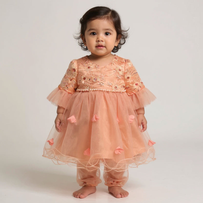 Child wearing a peach-colored dress with floral embroidery