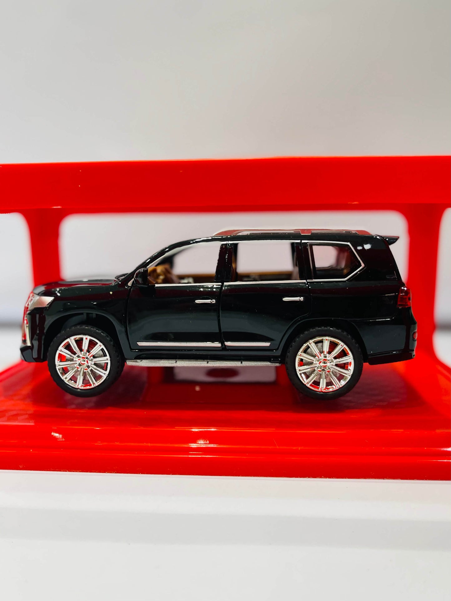 Black SUV model on a red stand with a white background