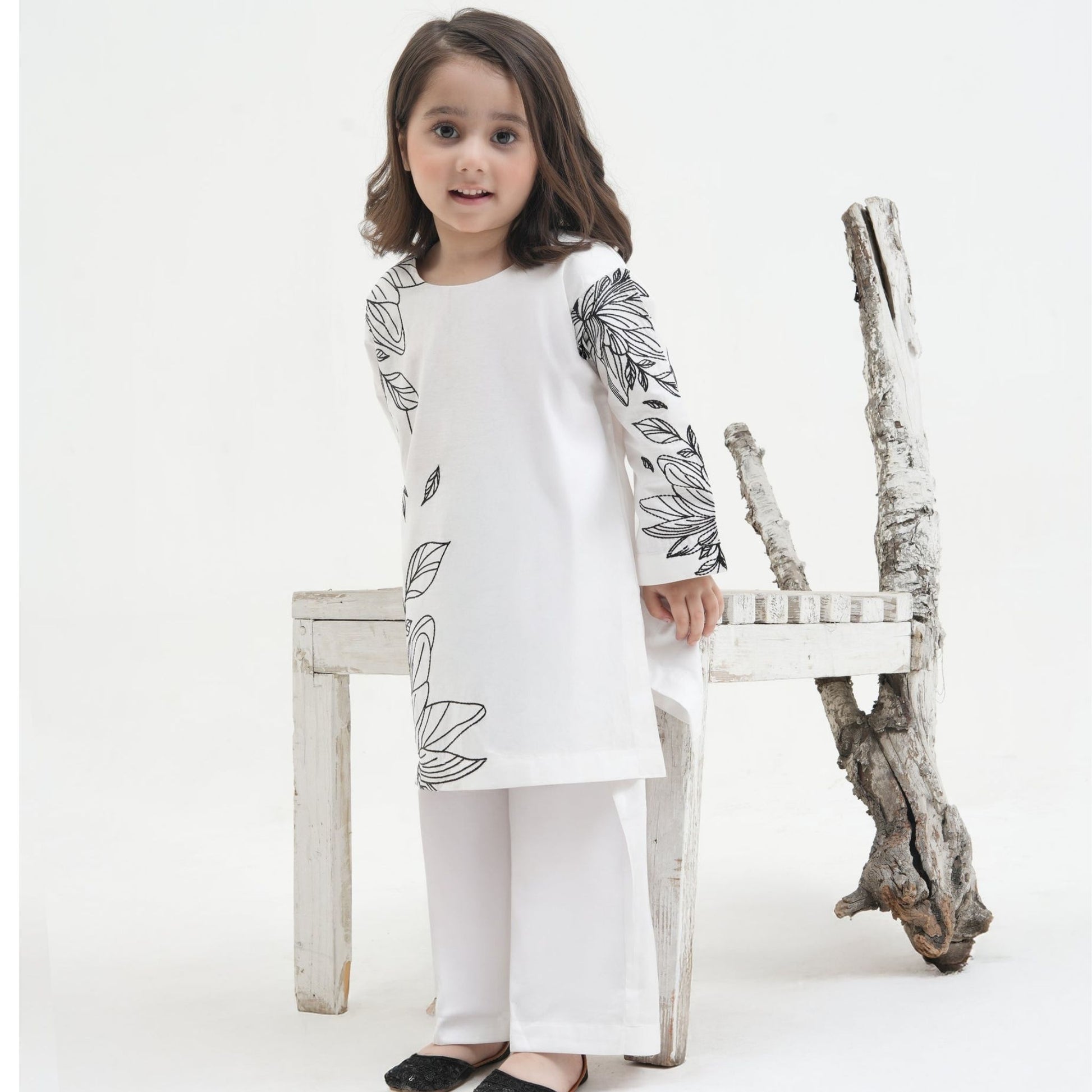 Child wearing a white traditional outfit with floral patterns