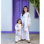 Woman and child in matching outfits standing in front of a purple door and white wall.