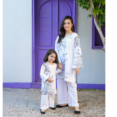 Woman and child in matching outfits standing in front of a purple door and white wall.