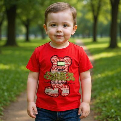 Child wearing a red t-shirt with a teddy bear design in a park