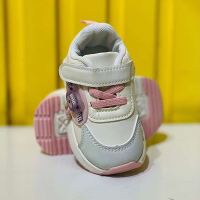 White and pink children's sneakers with a yellow background