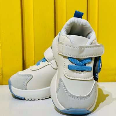White and blue children's sneakers on a yellow background