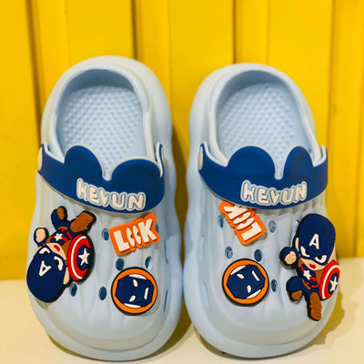 Pair of white clogs with superhero-themed decorations on a yellow background