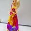 Barbie doll in a colorful dress with a plain background
