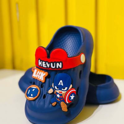 Blue children's clogs with superhero design and visible brand name on a yellow background
