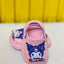 Pink children's clogs with cartoon character design on a yellow background