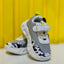 Gray and white children's shoes with cow print on a yellow background