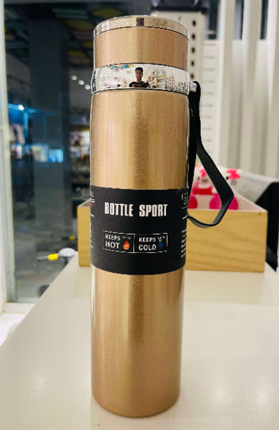 Gold insulated bottle with black label on a white surface