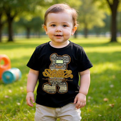 Child wearing a black t-shirt with a gold graphic design in a park