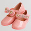 Pink children's shoes with decorative bows on a light gray background