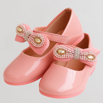 Pink children's shoes with decorative bows on a light gray background