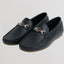 Black leather loafers with brand logo on a light gray background
