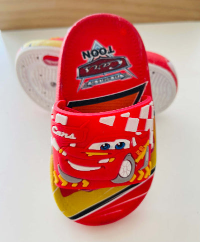 Red children's sandals with cartoon character design on a white surface.