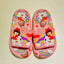 Pink children's sandals with cartoon characters on a light pink background