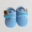 Pair of blue baby shoes with 'Happy' and bear design on a light gray background