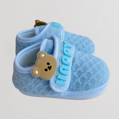 Blue baby sandal with a teddy bear design on a light gray background