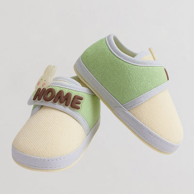 Pair of baby shoes with 'HOME' text on a light gray background