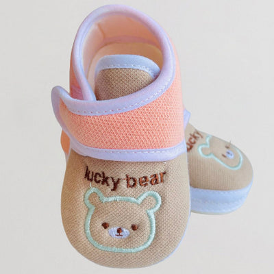 Baby shoes with 'lucky bear' design on a light background