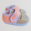 Pair of baby shoes with pink and beige design on a light background