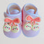 Pair of baby shoes with pink bows and bear charms on a light background