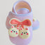 Pink sandal with a bow and cartoon character design on a light gray background