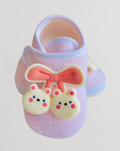 Pink sandal with a bow and cartoon character design on a light gray background