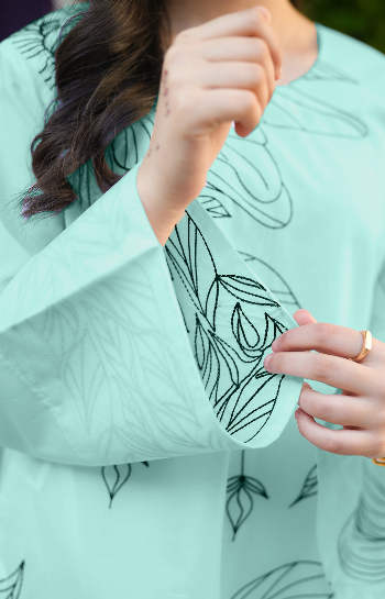 Person wearing a light green dress with black leaf patterns.