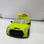 Green toy car on a white surface with a blurred background