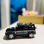 Black toy SUV with red wheels on a white surface