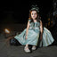 Young girl in a sparkly dress sitting on a stone surface with a dark background
