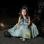 Young girl in a green dress sitting on the ground with a dark background