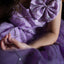 Close-up of a person wearing a purple dress with decorative elements.